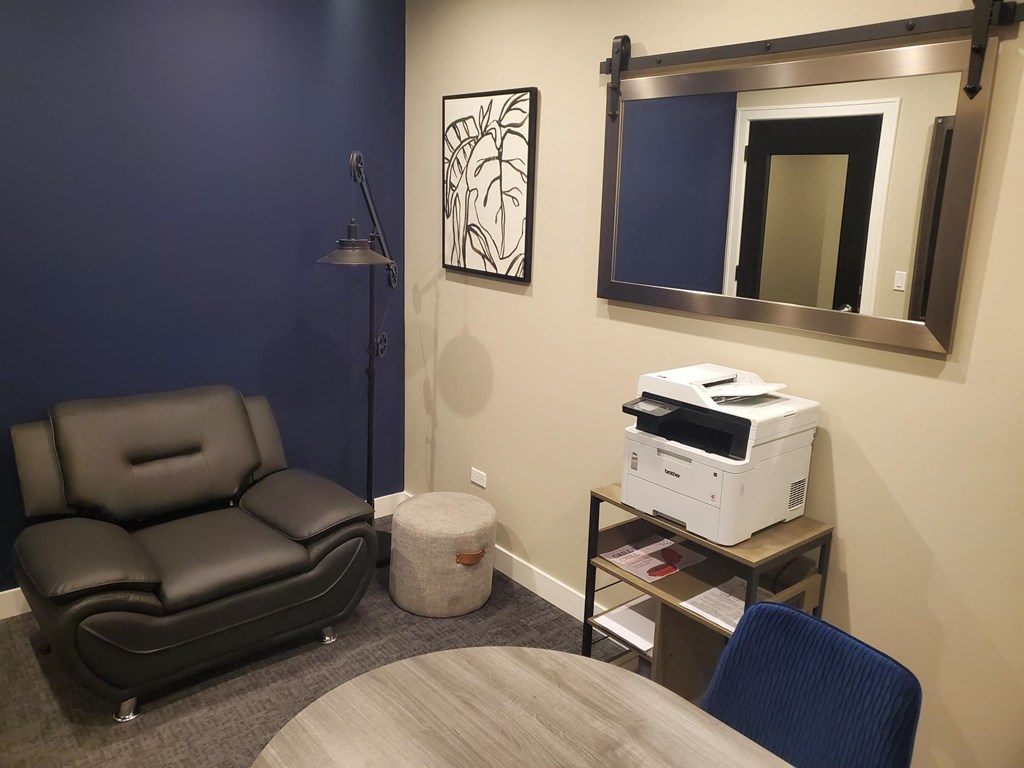 a small living room with a chair and a table and a printer