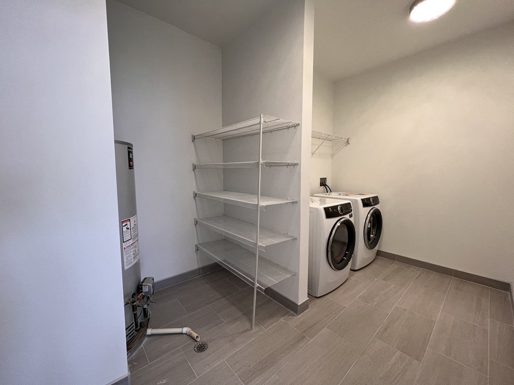 a washer and dryer in a laundry room with white walls and tile floor