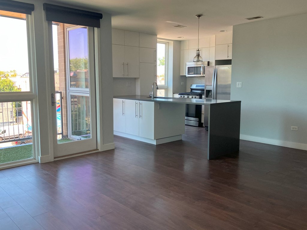 an open kitchen and living room with a wooden floor