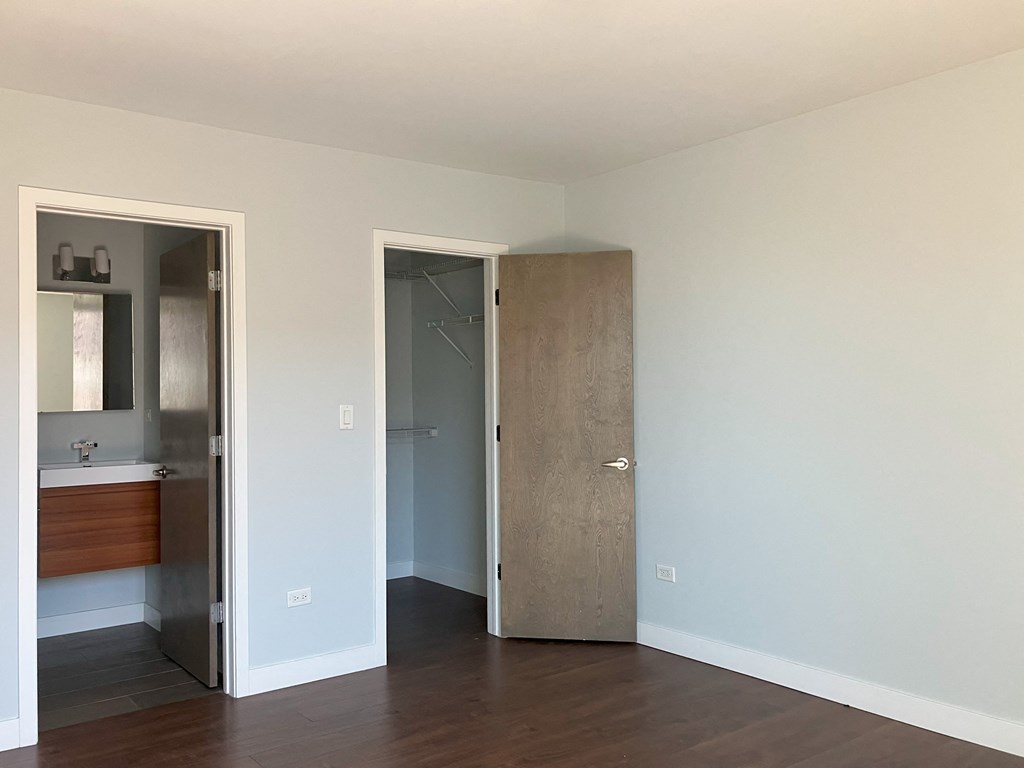an empty room with a door to a bathroom and a mirror