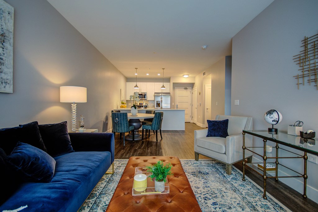 a living room with a blue couch and a coffee table in front of a kitchen at Barrington 101, Chicago