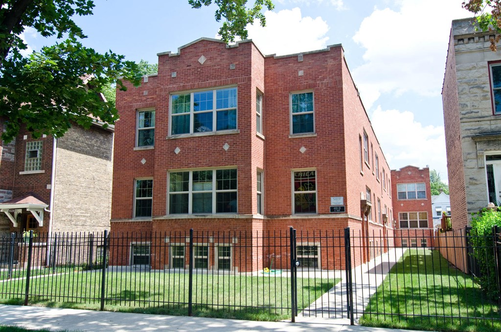a red brick building with a black fence in front of it at Tripp 4321, Chicago, 60641