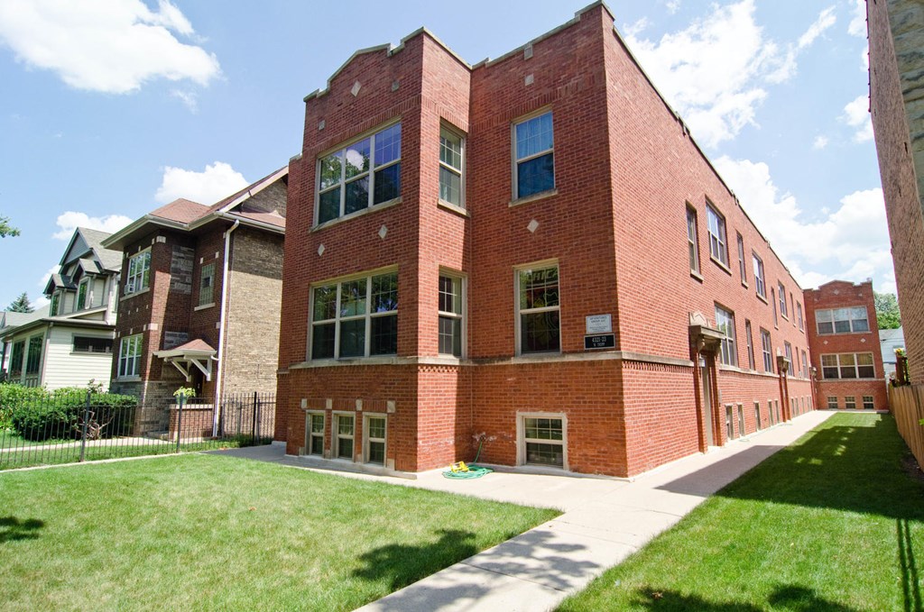 a red brick building with a sidewalk and grass at Tripp 4321, Chicago, 60641