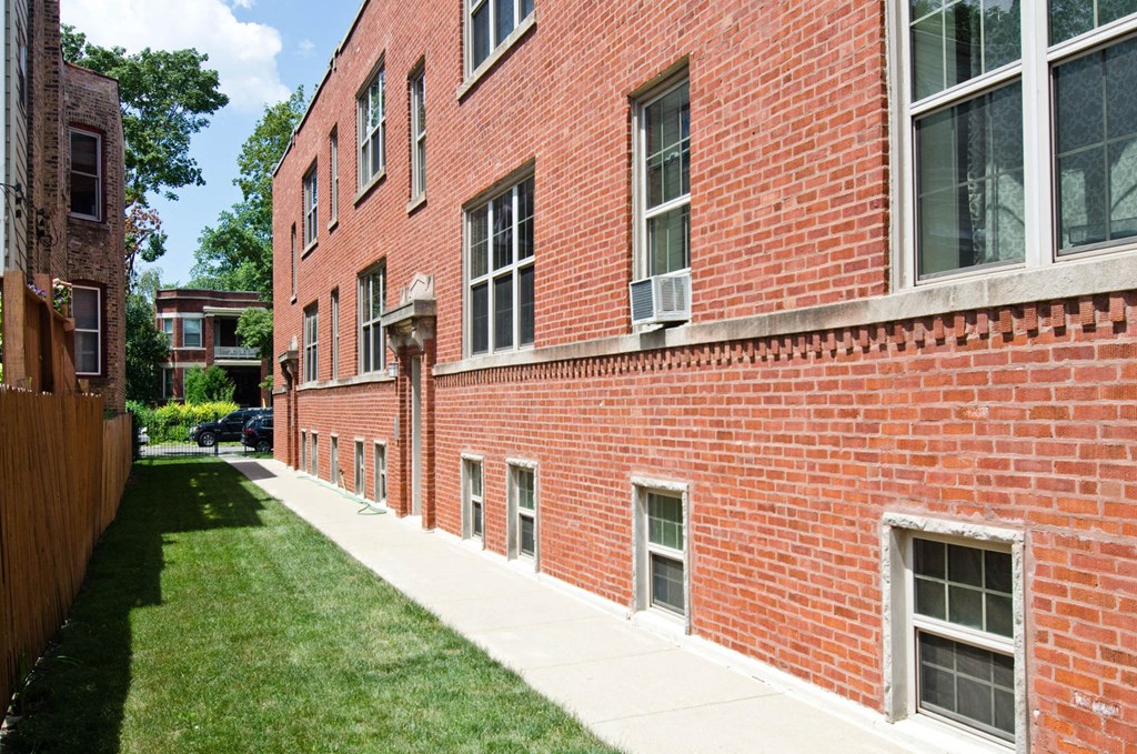 the side of a brick building with a sidewalk and grass at Tripp 4321, Chicago