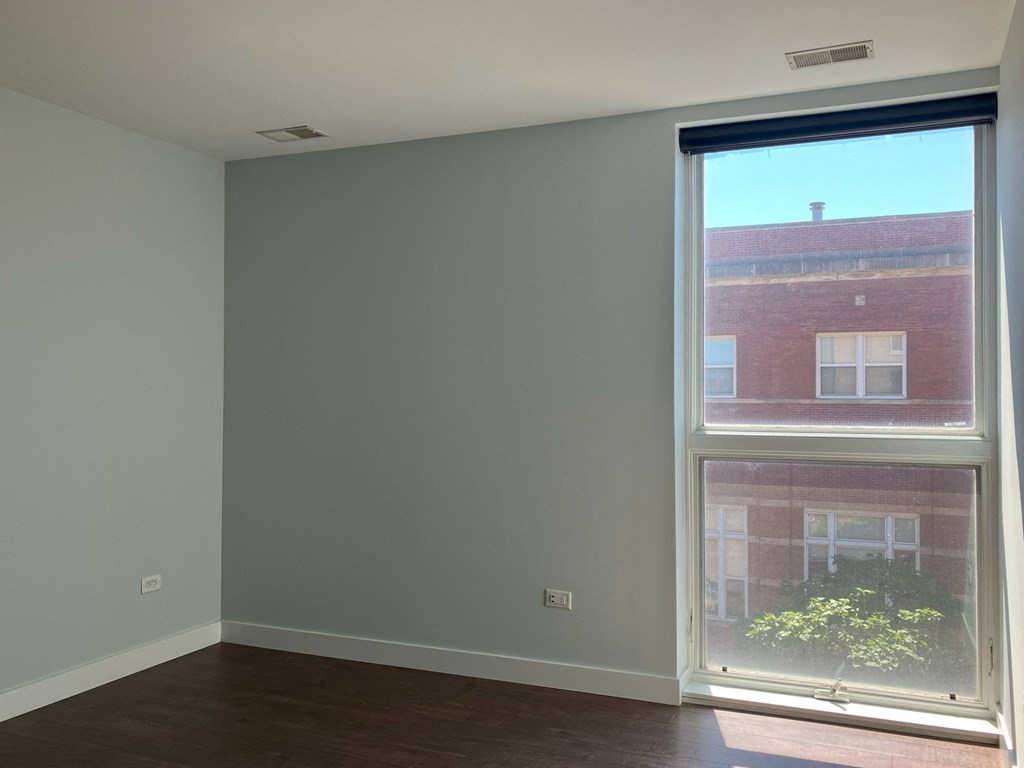 an empty room with a large window and a wooden floor