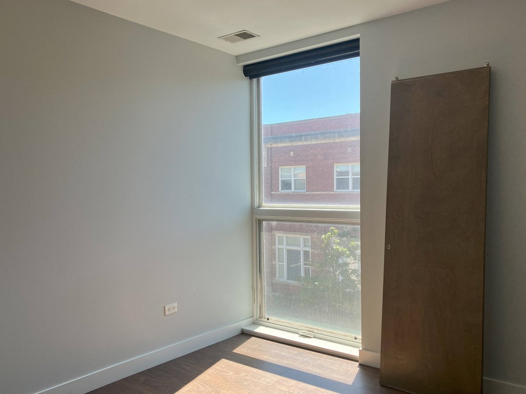a bedroom with a large window and a wooden door