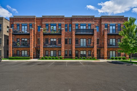 A large red brick building with a parking lot in front.