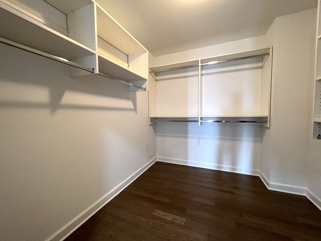 a living room with a wood floor and white walls and a closet with a window