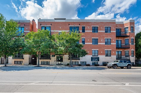 A red brick building with a black car parked in front.