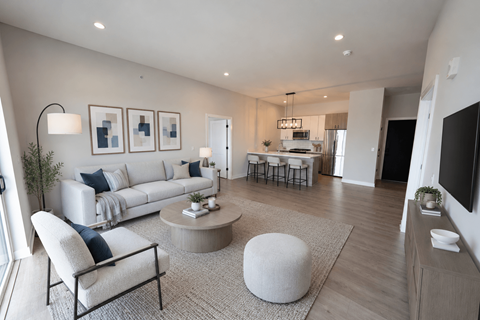 A modern living room with a white sofa, a grey ottoman, and a black chair.
