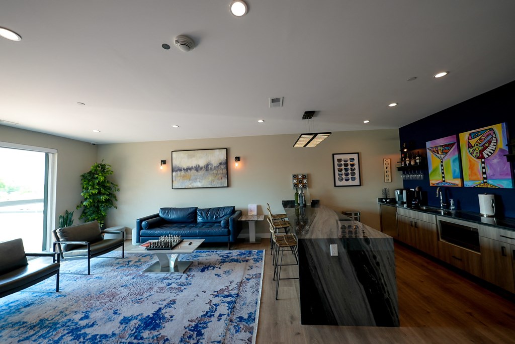 a living room with a kitchen and a blue rug