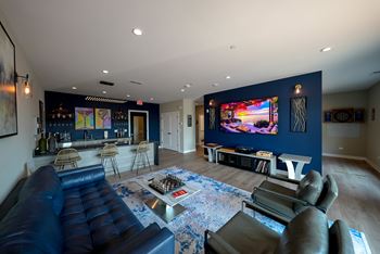 A modern living room with a large blue couch and a flat screen TV mounted on the wall.