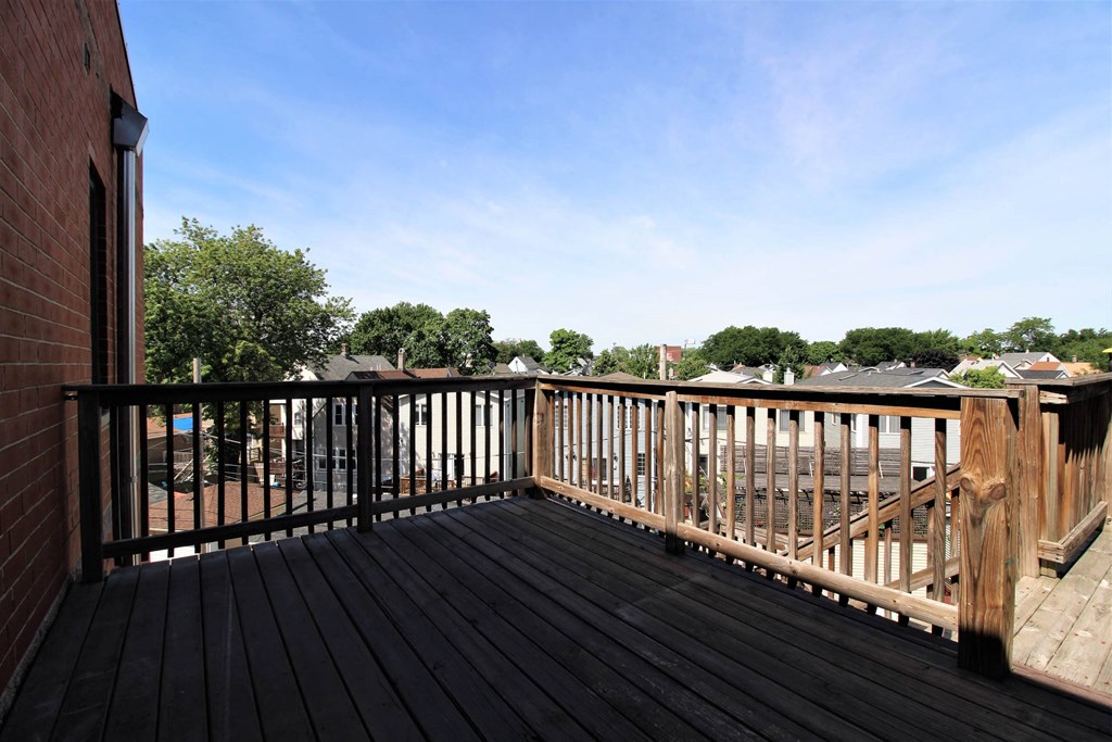 a balcony with a wooden railing and a blue sky  at Elston 3434, Chicago, IL