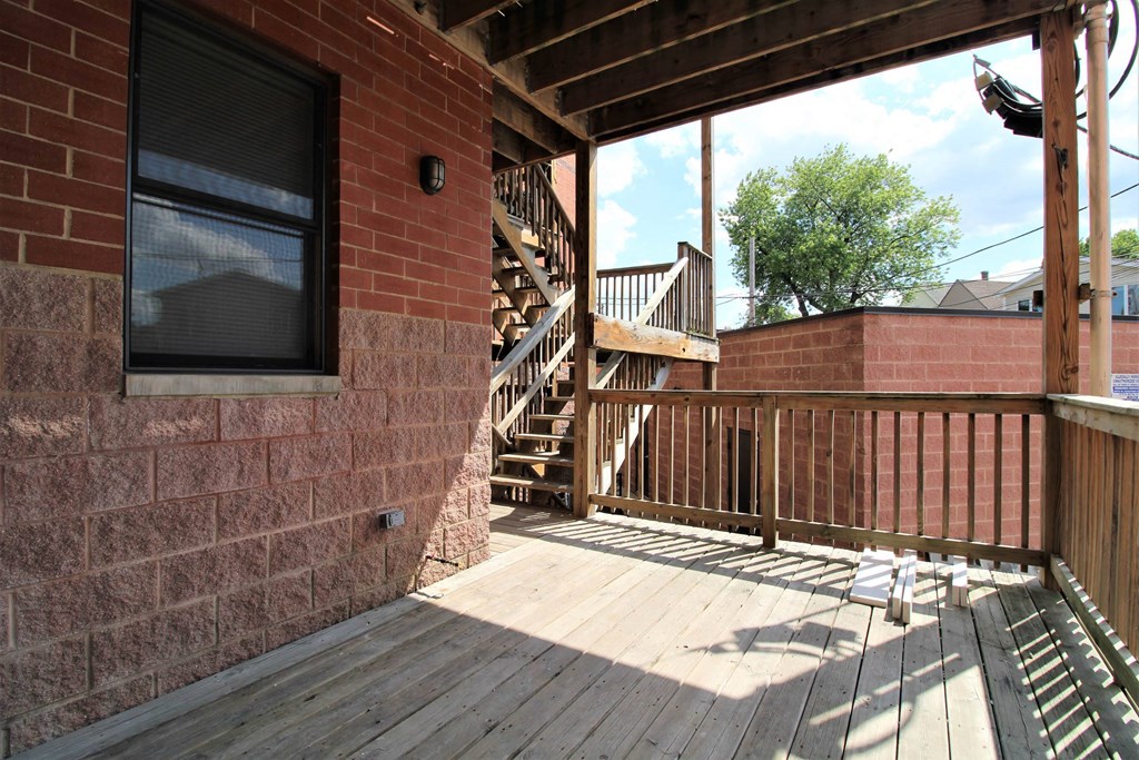 a porch with a wooden deck next to a brick house  at Elston 3434, Chicago, IL, 60618