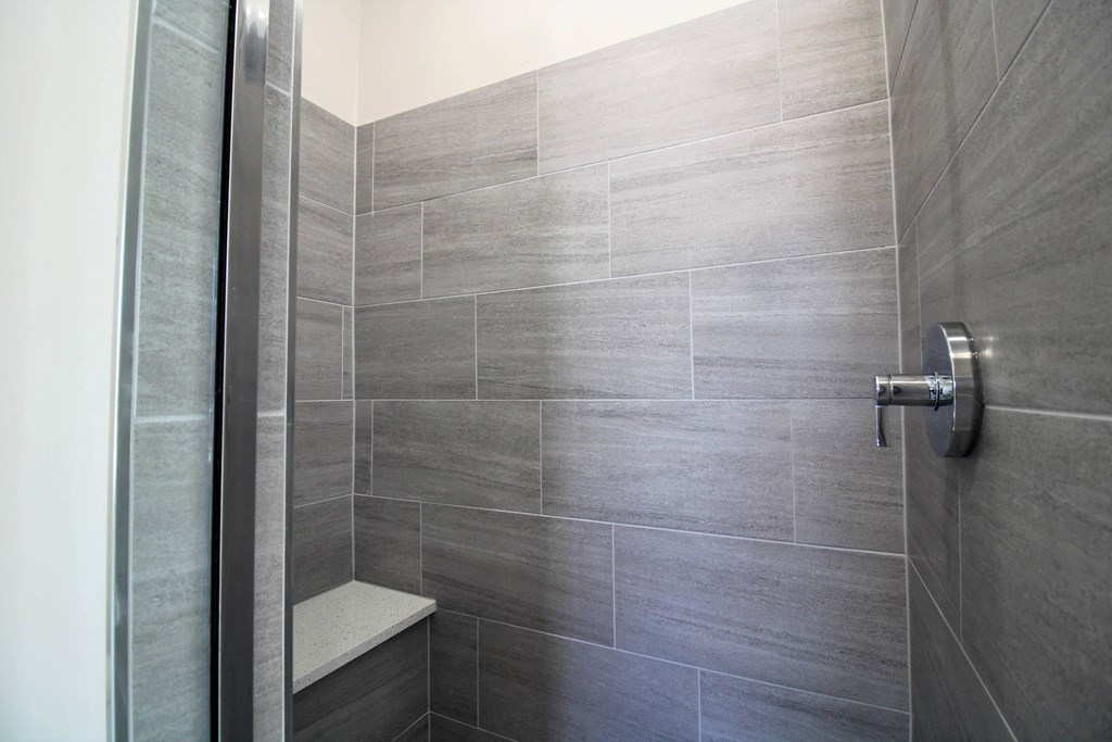 a grey tiled shower in a bathroom with a glass door  at Elston 3434, Illinois, 60618