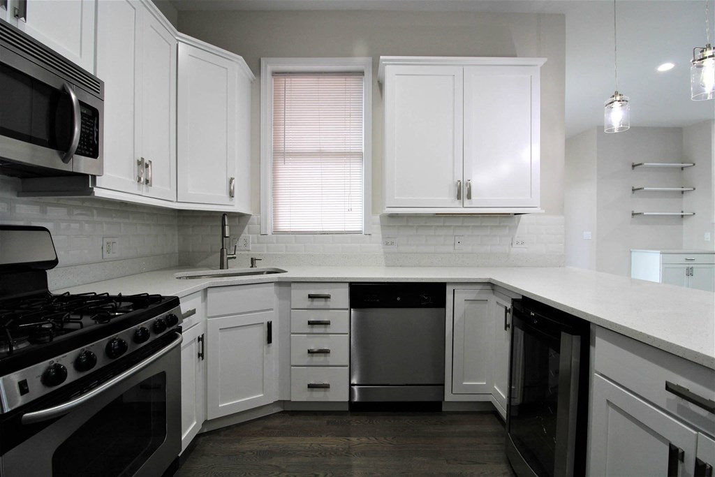 a kitchen with white cabinets and black appliances  at Elston 3434, Chicago, 60618