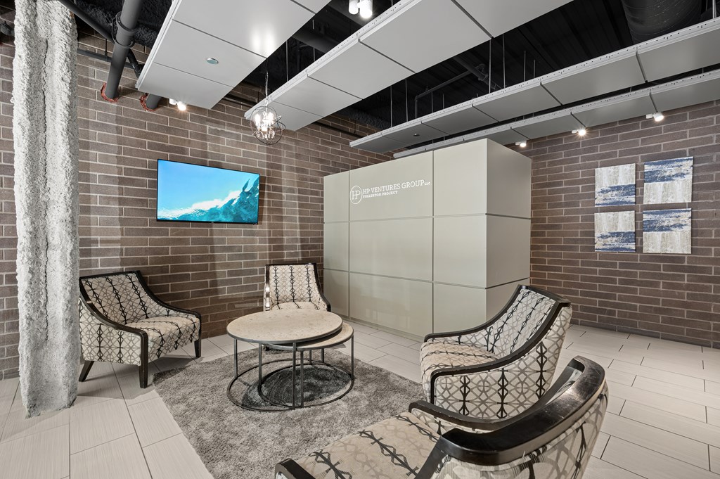 A room with a television on the wall and chairs around a table.