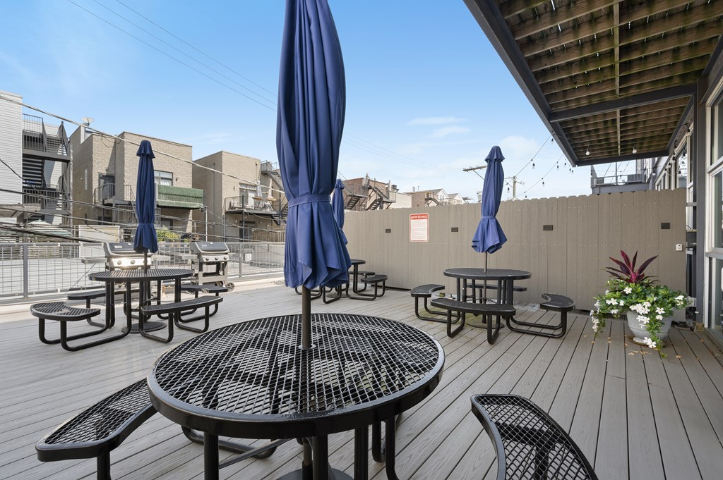 A patio with tables and chairs and umbrellas.