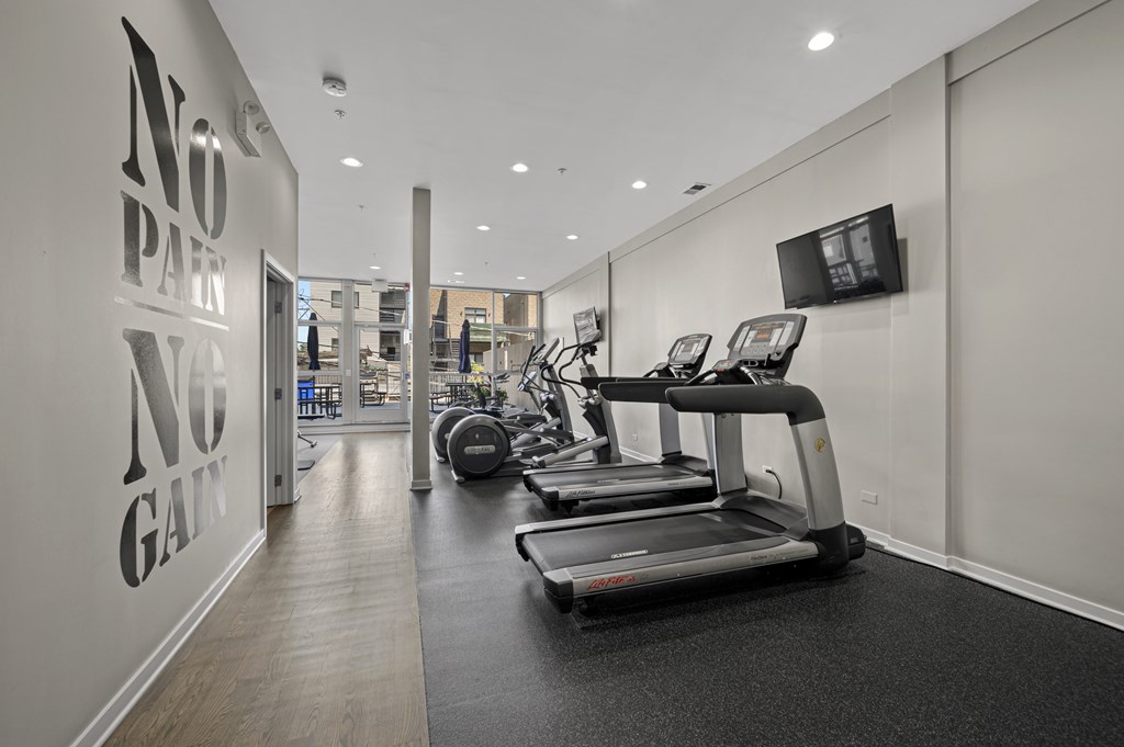 A gym with treadmills and a wall that says