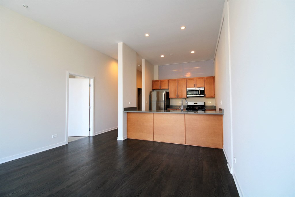 a living room with wood flooring and a kitchen