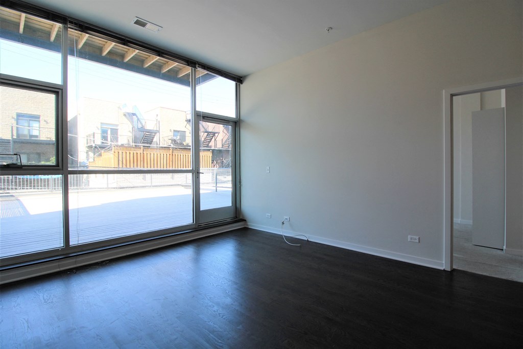 an empty living room with a large window and wood flooring