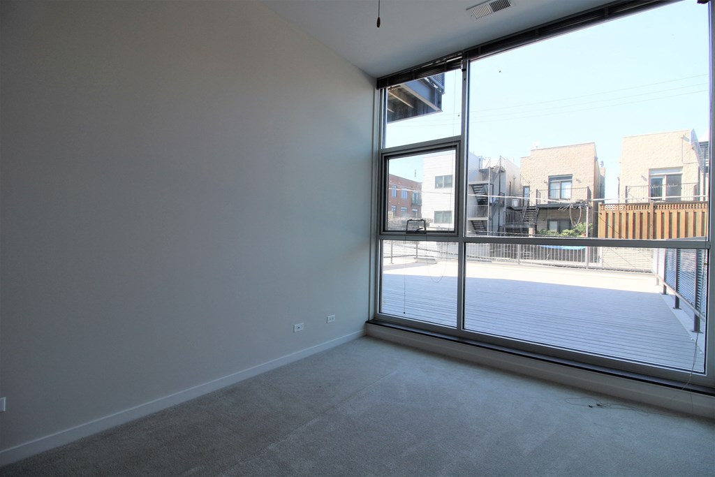 an empty living room with a large window and a balcony