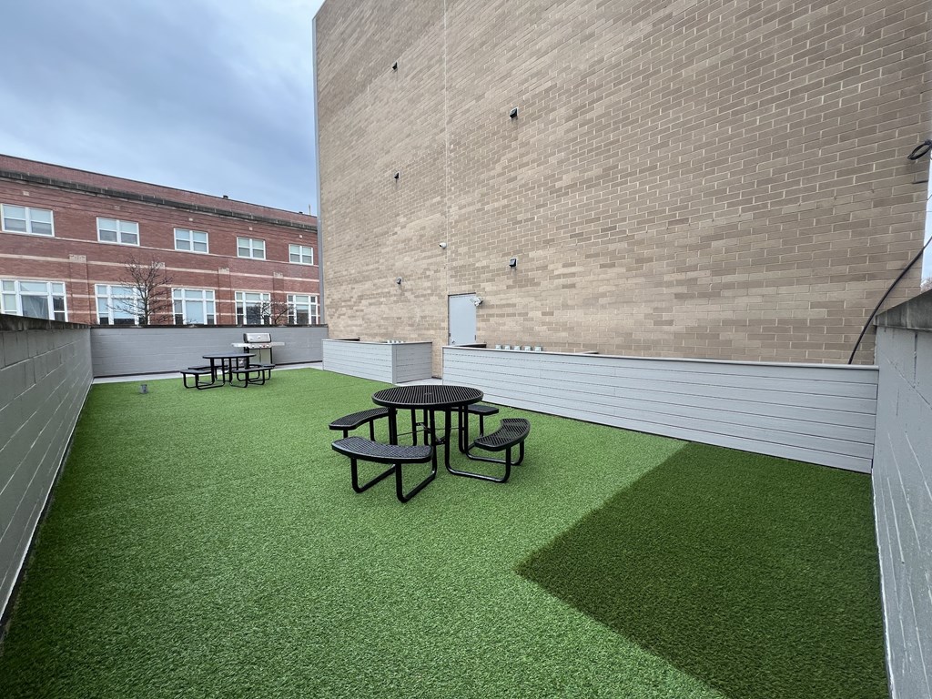 a roof deck with a table and chairs on a green lawn