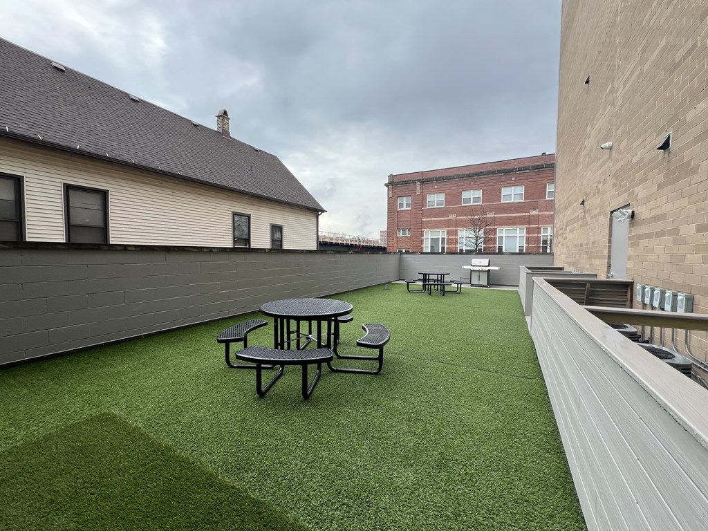 a rooftop patio with a green lawn and tables