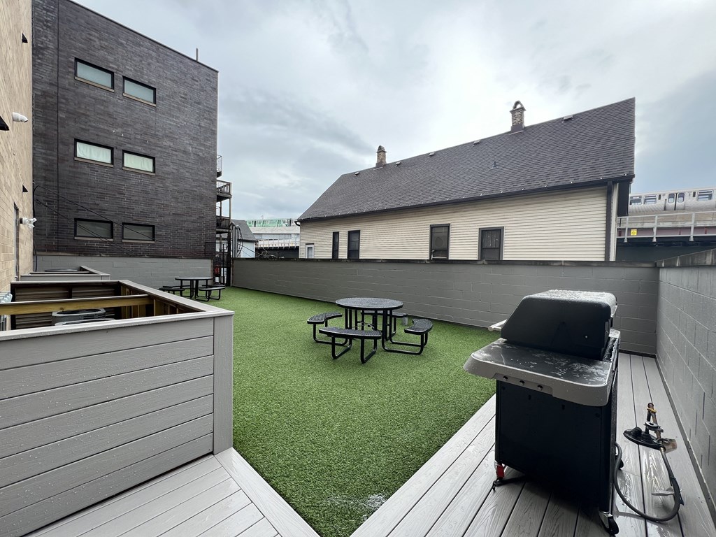 a roof deck with a grill and a picnic table on a green turf