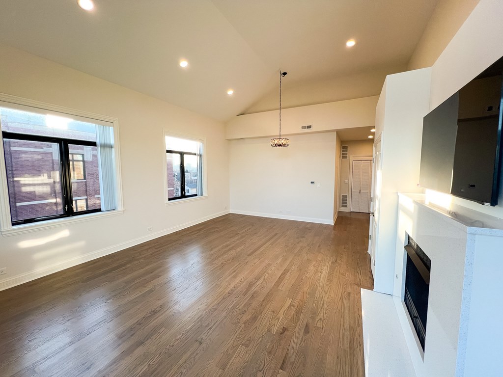A spacious living room with wooden flooring and a fireplace.