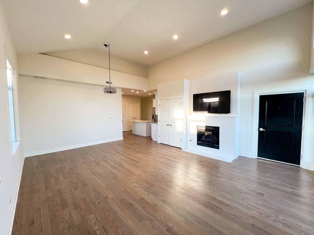 A spacious room with wooden flooring and a television mounted on the wall.