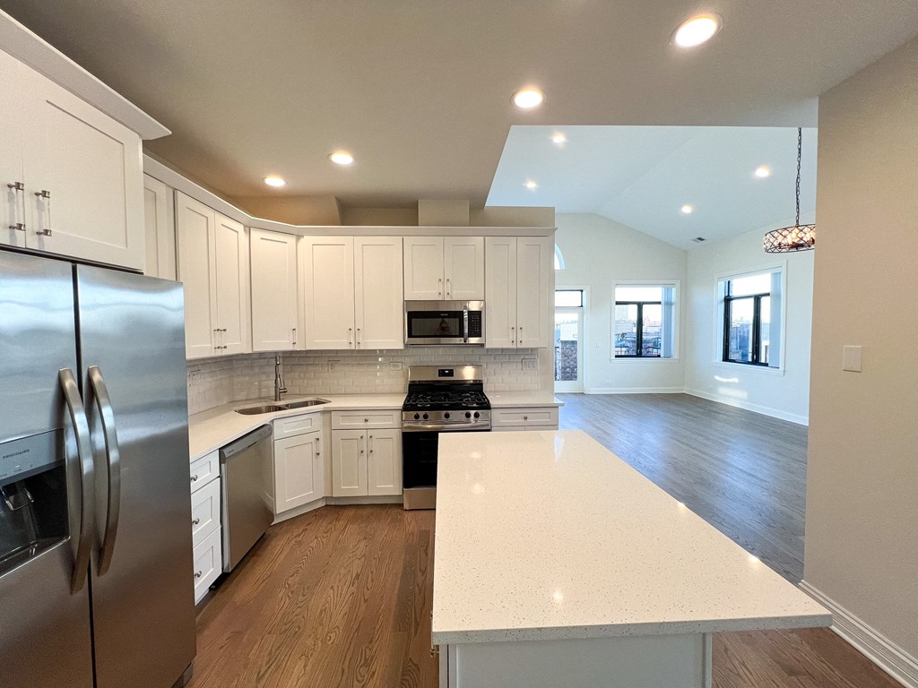 A modern kitchen with white cabinets and a stainless steel refrigerator.