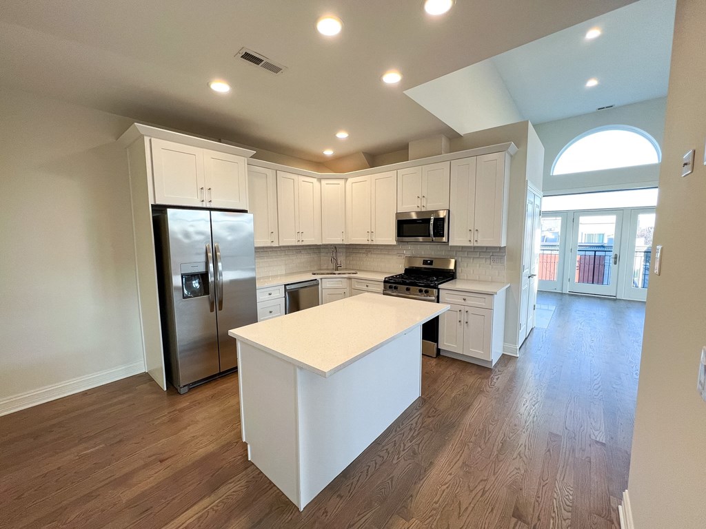 A kitchen with white cabinets and a white island.