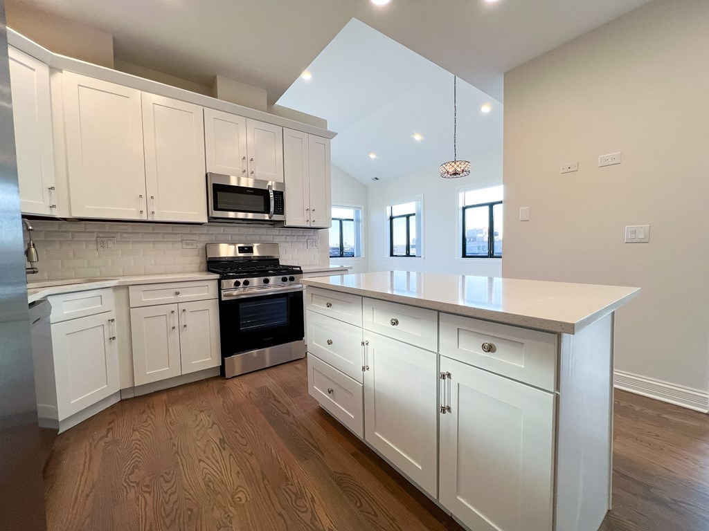 A kitchen with white cabinets and a wooden floor.