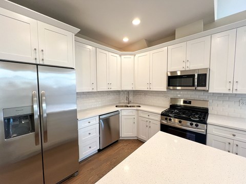 A kitchen with white cabinets and a stainless steel refrigerator.