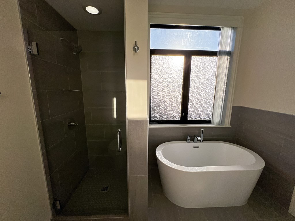 A white bathtub is in a bathroom with a glass shower door.