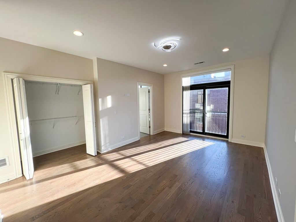 A large empty room with wooden floors and white walls.