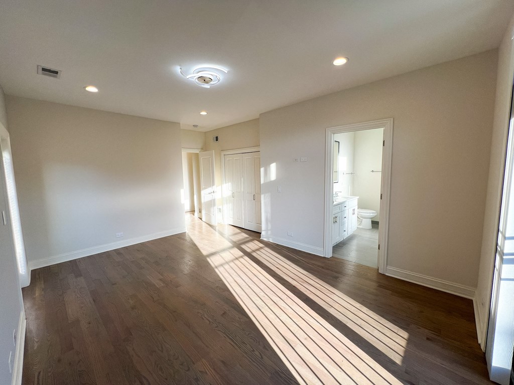 A spacious room with wooden floors and white walls.