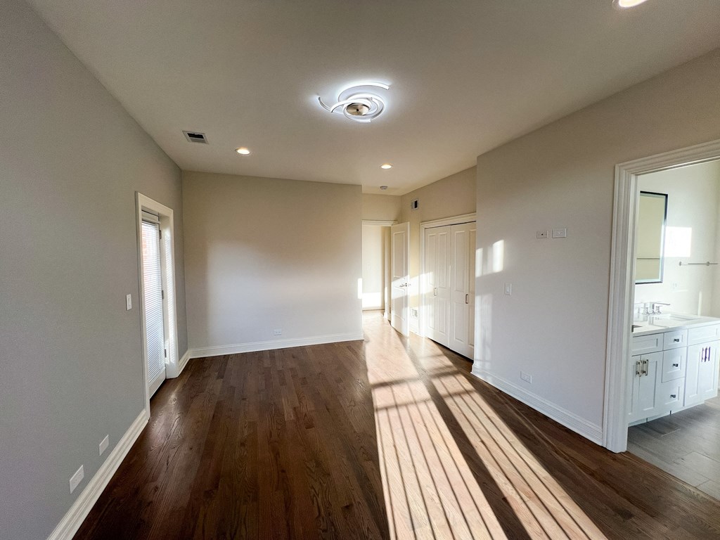 A spacious room with wooden floors and white walls.