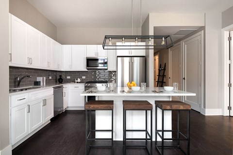 a kitchen with white cabinets and a center island with three stools