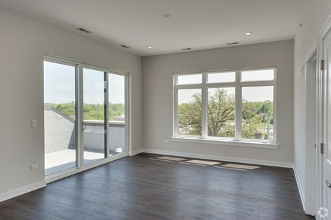 an empty living room with large windows and a balcony