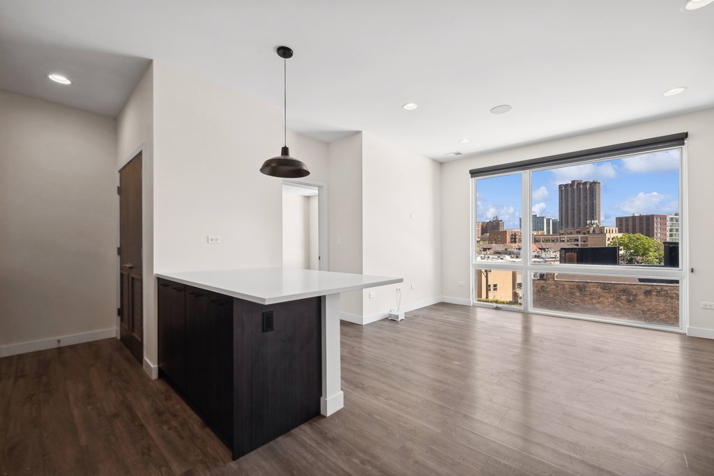 Open kitchen and living room at Highpoint Buena Park on Broadway featuring modern finishes, stainless steel appliances, and floor-to-ceiling windows with city views in a Chicago apartment