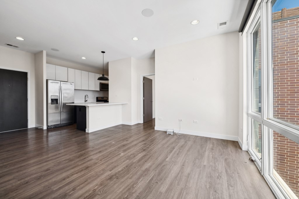 Corner view of open-concept kitchen, dining, and living area at Highpoint Buena Park on Broadway featuring large windows, modern finishes, and seamless flow in a bright Buena Park apartment in Chicago