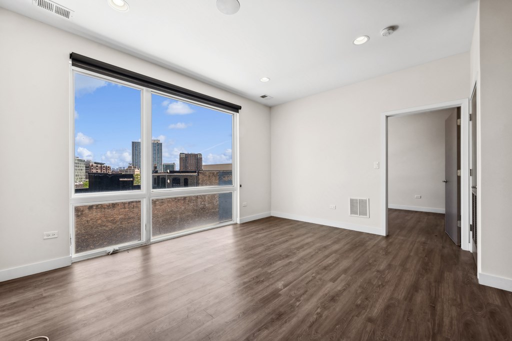 Living room at Highpoint Buena Park on Broadway with modern hardwood floors, large windows, and open sightlines to the kitchen in a contemporary Buena Park apartment near the Sheridan Red Line Station in Chicago
