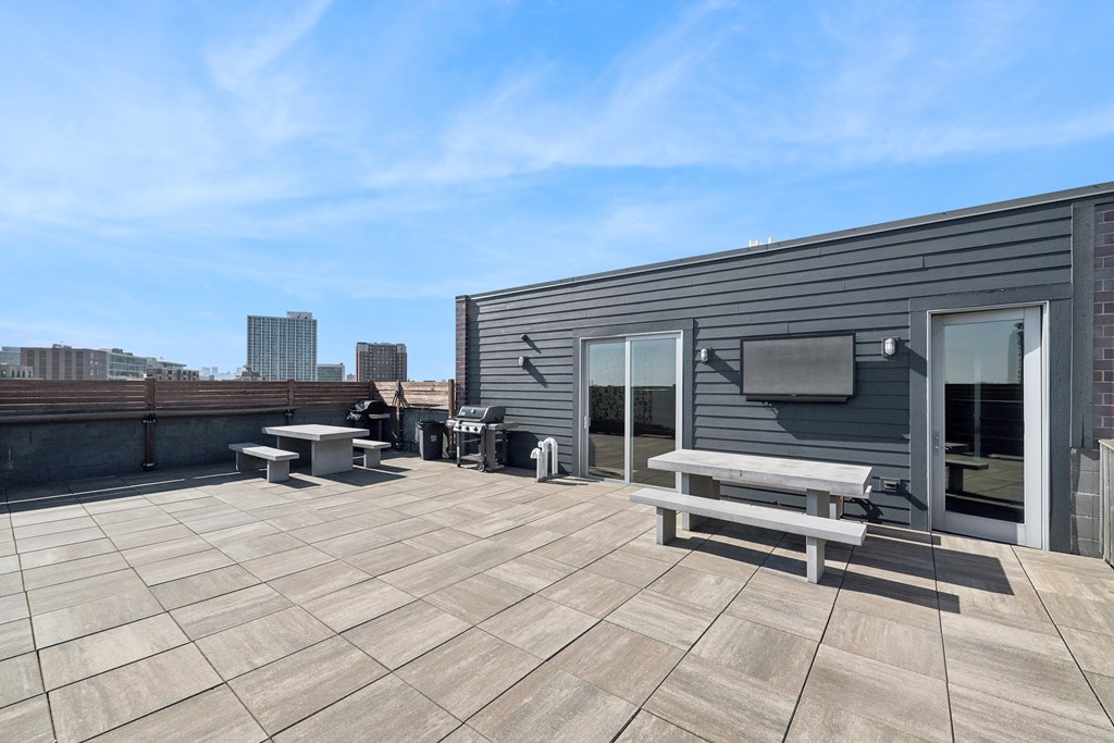 A rooftop patio with a table and chairs and a television.
