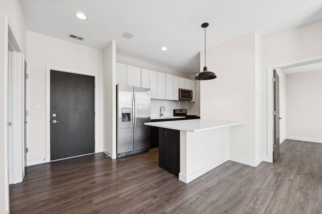 A modern kitchen with a black door and a white countertop.