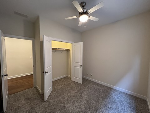 an empty bedroom with a ceiling fan and a closet