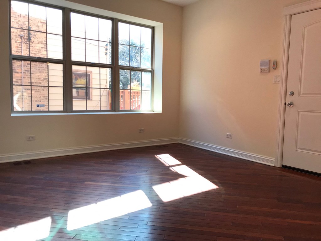 an empty living room with sunlight coming through a window at Tripp 4321, Chicago, IL