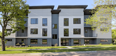 a white and gray apartment building with trees in front of it