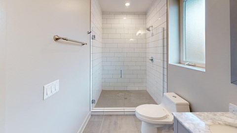A white toilet is in a bathroom with a walk-in shower.